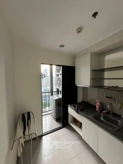 Compact kitchen with balcony view and modern appliances in urban apartment