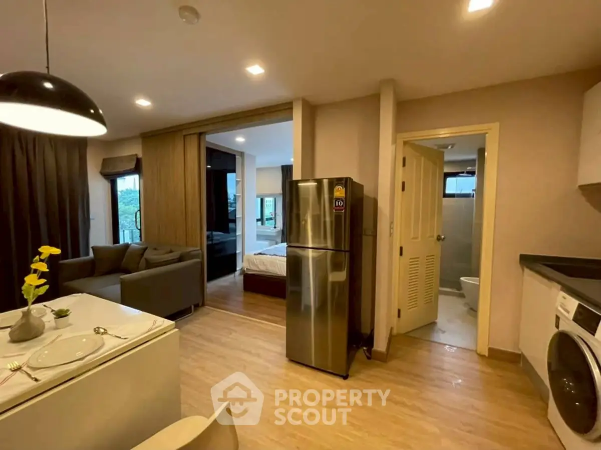Modern open-plan apartment with kitchen, living area, and bedroom, featuring sleek appliances and stylish decor.