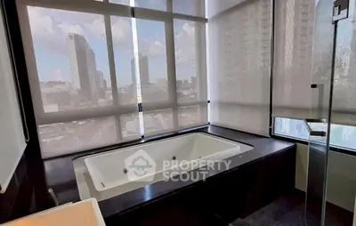 Luxurious bathroom with city view and modern bathtub in high-rise apartment.
