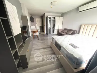 Modern studio apartment with stylish furniture and sleek flooring, featuring a cozy bed and compact kitchen area.