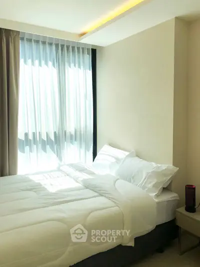 Bright and cozy bedroom with modern decor and large window for natural light.