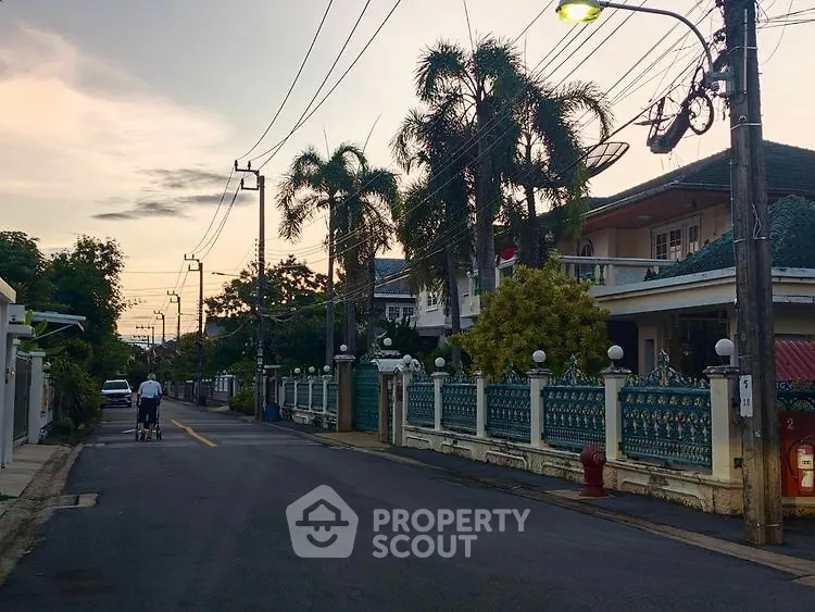 Charming suburban street with palm trees and elegant homes at sunset.