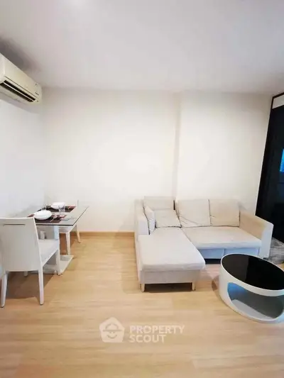 Modern living room with beige sofa and glass dining table, featuring minimalist decor.