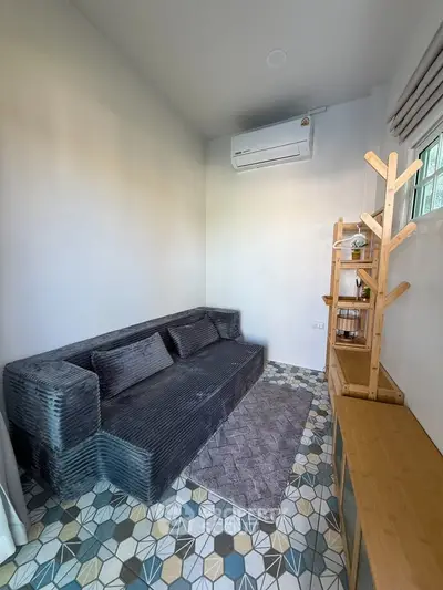 Cozy living room with modern sofa, air conditioning, and stylish geometric floor tiles.