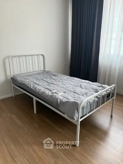 Minimalist bedroom with single bed and wooden flooring, perfect for cozy living.
