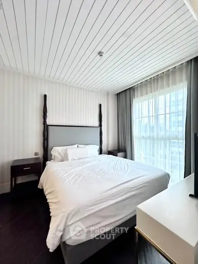 Elegant bedroom with modern decor and large window offering natural light.