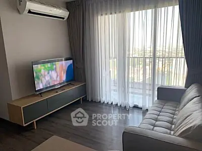 Modern living room with sleek furniture and large window offering natural light and city view.