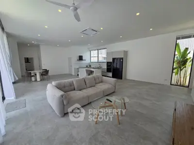 Spacious open-plan living room with modern kitchen and stylish furnishings in a bright, airy home.