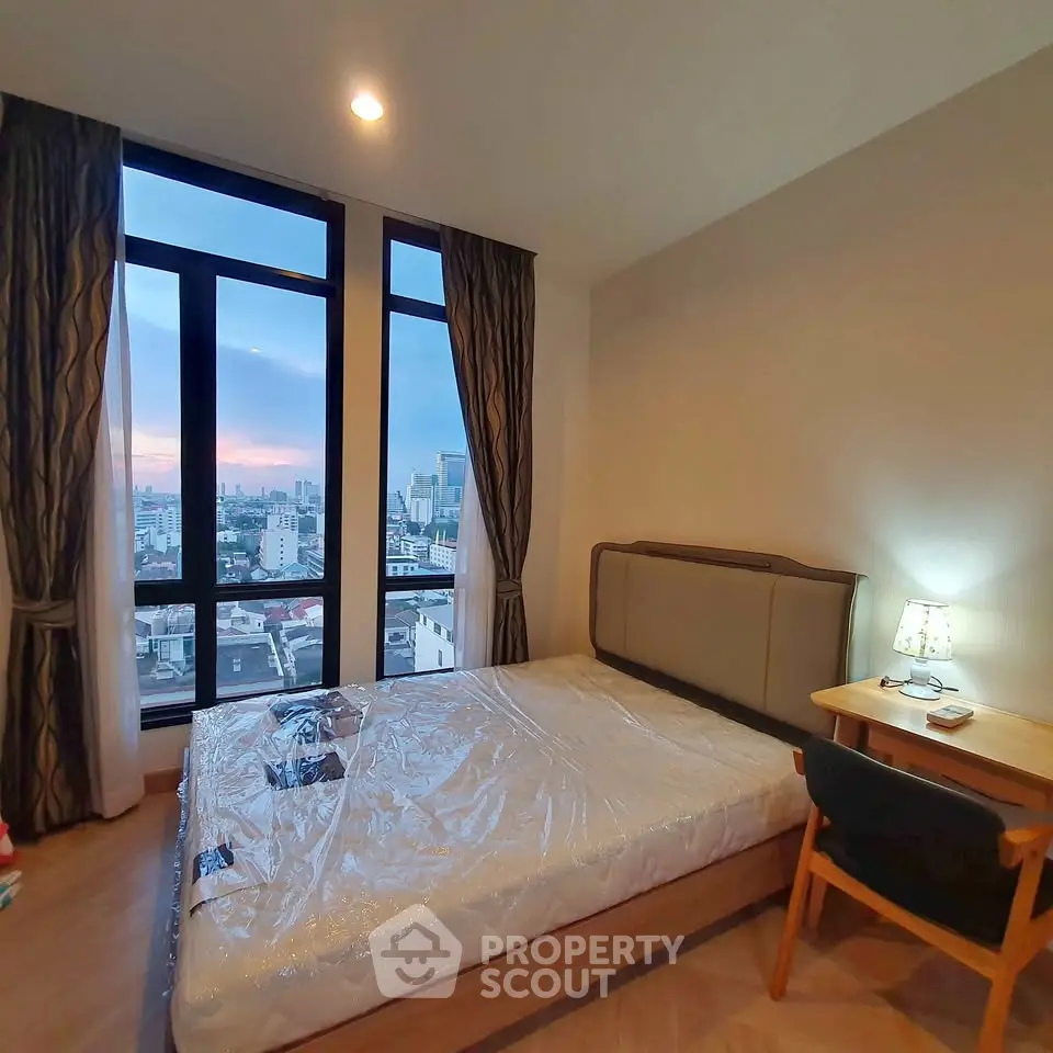 Cozy bedroom with city view and modern furnishings in high-rise apartment.