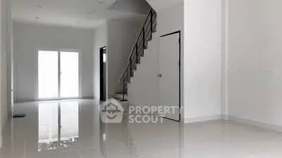 Spacious modern living room with sleek staircase and glossy tiled floors.