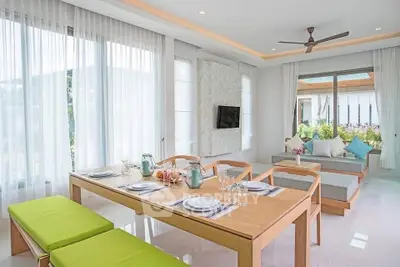 Modern dining area with natural light and garden view, featuring elegant table setting and cozy seating.