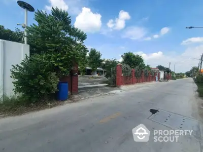 Charming suburban street view with lush greenery and red brick entrance