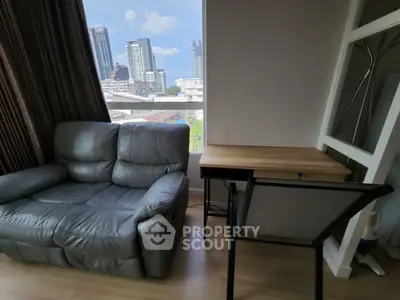 Modern living room with city view, featuring a cozy sofa and a sleek desk setup.