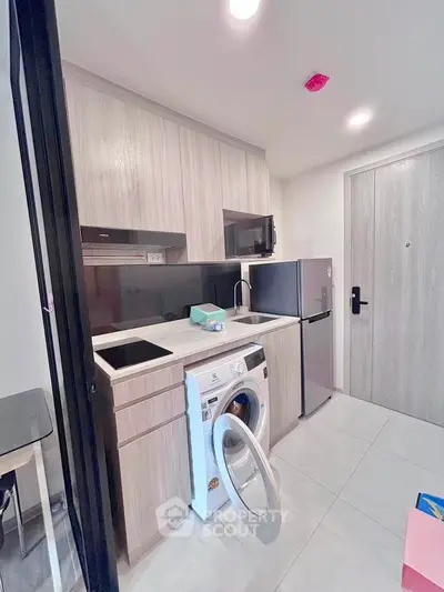 Modern compact kitchen with washing machine and fridge in stylish apartment