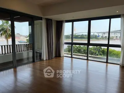 Spacious living room with large windows offering stunning river and bridge views.
