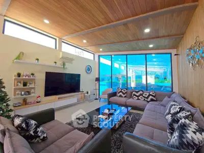 Spacious modern living room with large windows, stylish furniture, and wooden ceiling, perfect for relaxation.