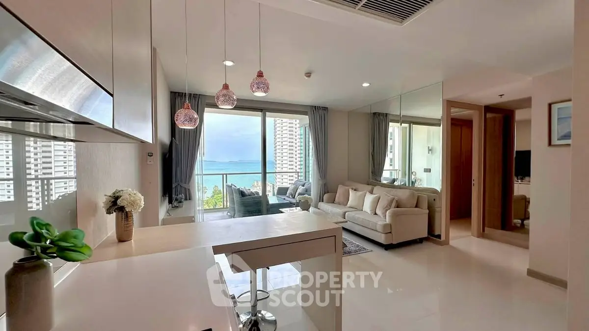 Modern living room with ocean view, open kitchen, and elegant decor in a high-rise apartment.