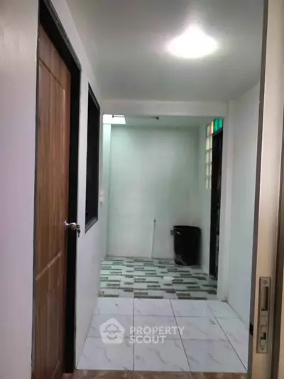 Simple hallway with tiled flooring and wooden door