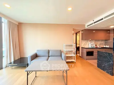 Modern living room with open kitchen, featuring sleek furniture and natural light.
