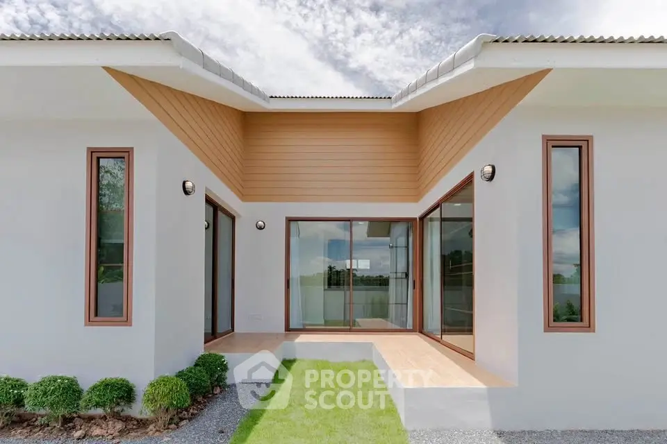 Modern minimalist house exterior with unique architectural design and lush green lawn.