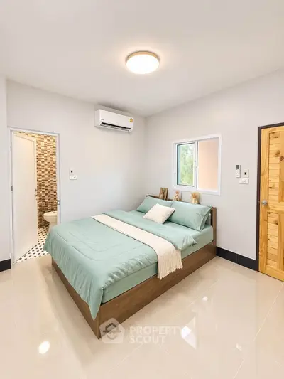 Modern bedroom with ensuite bathroom, featuring a cozy bed and sleek air conditioning unit.