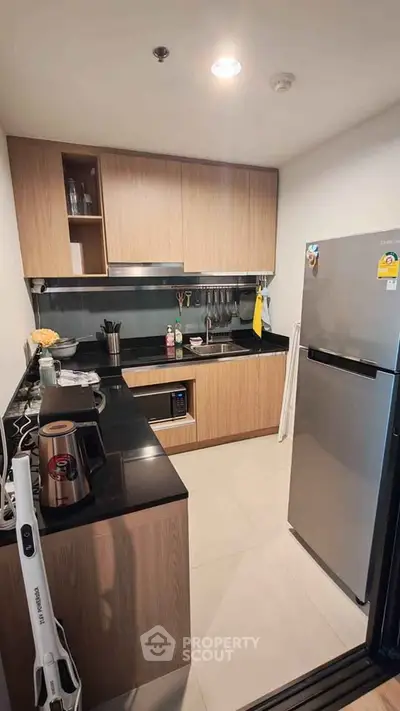Modern kitchen with sleek appliances and wooden cabinetry in a compact layout.