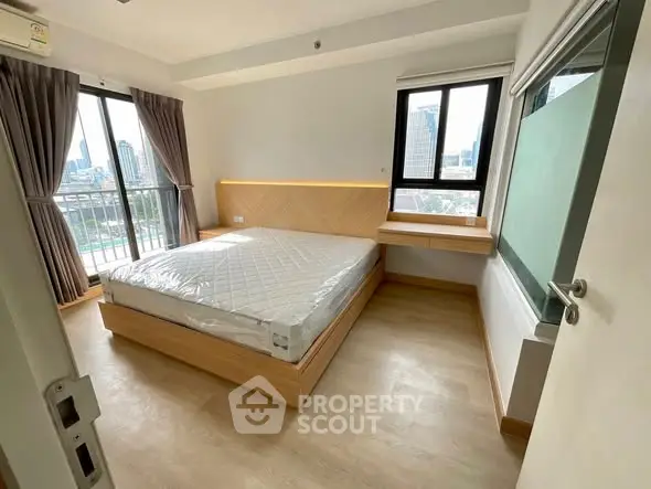 Modern bedroom with large windows and city view, featuring a stylish bed and wooden flooring.