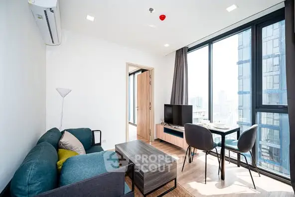 Modern living room with large windows and stylish furniture in a high-rise apartment.