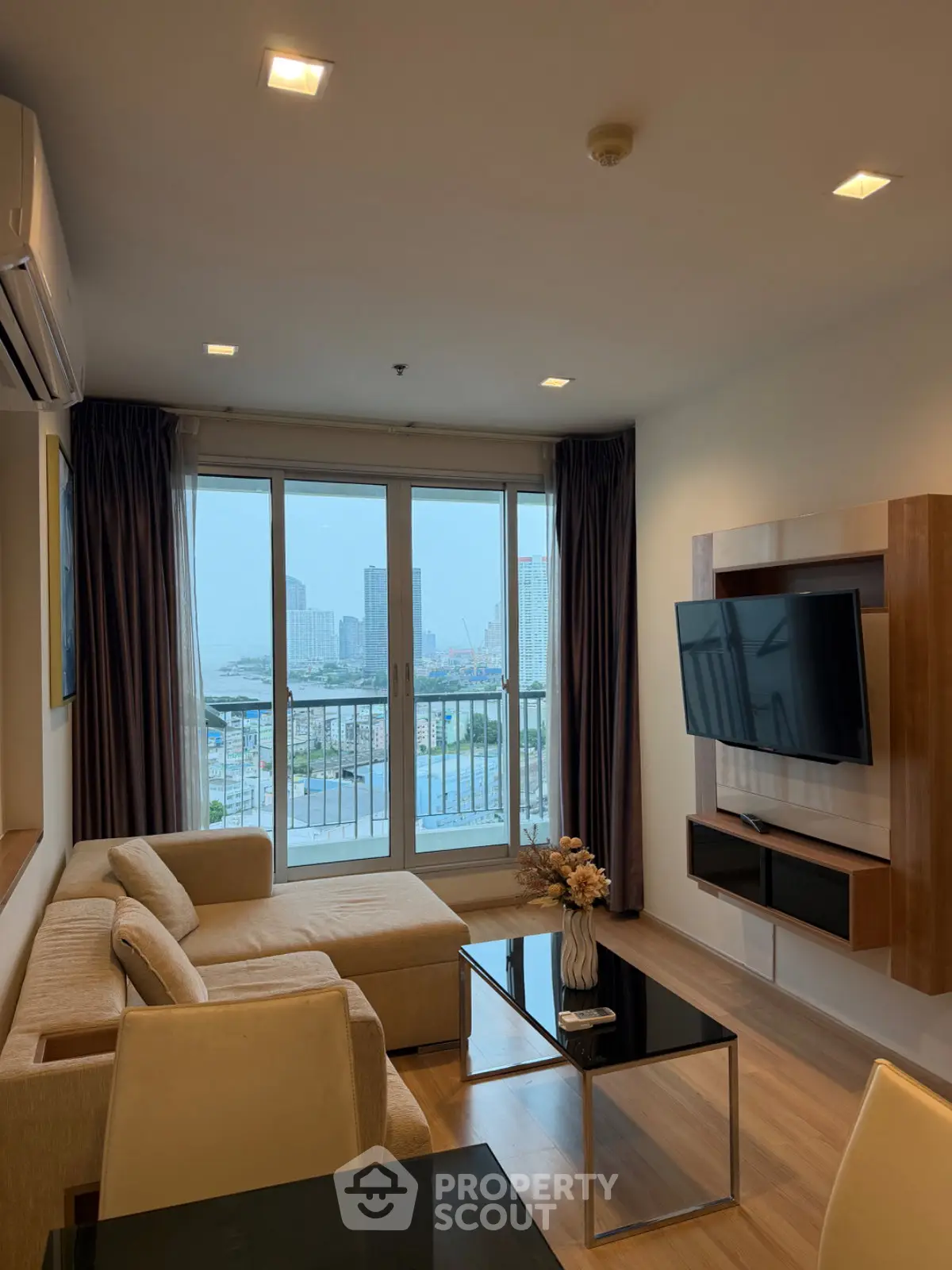 Modern living room with city view, featuring sleek furniture and large windows for natural light.