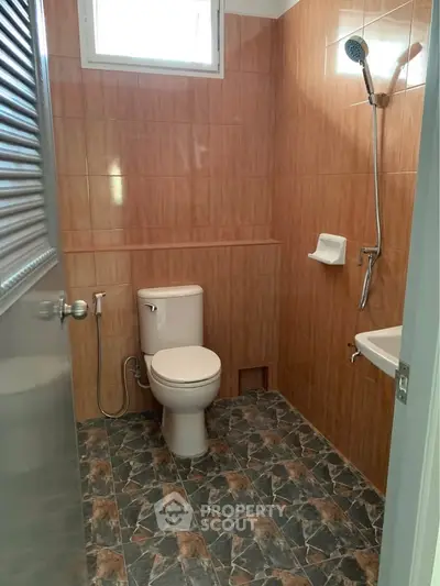 Compact bathroom with tiled walls and floor, featuring a shower and toilet.