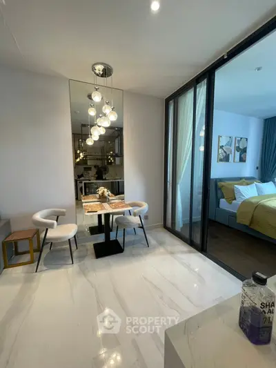 Modern dining area with elegant lighting and glass partition leading to cozy bedroom.