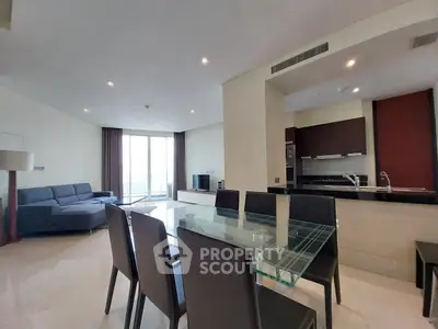 Spacious open-plan living room with modern kitchen and dining area, featuring sleek furniture and ample natural light.