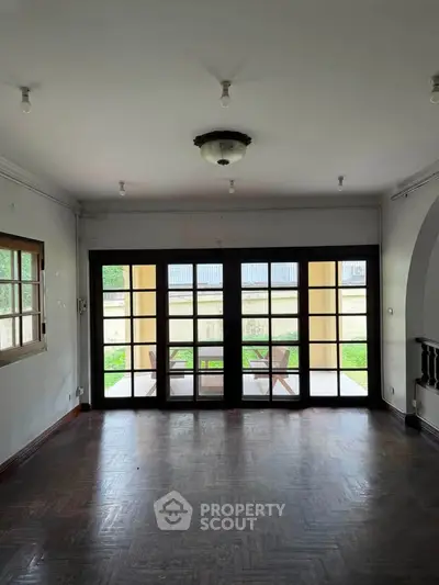 Spacious living room with large windows and garden view, perfect for natural light and outdoor access.