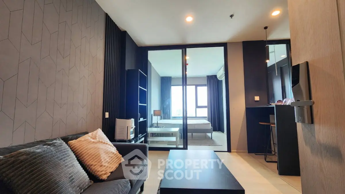 Modern open-layout living room with stylish decor and view into a cozy bedroom.