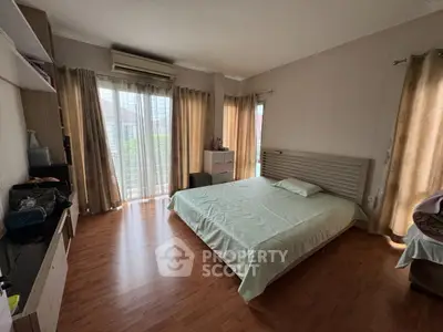 Spacious bedroom with wooden flooring and natural light, featuring a cozy bed and modern decor.