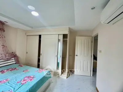 Cozy bedroom with floral bedding and built-in wardrobe, featuring modern air conditioning.
