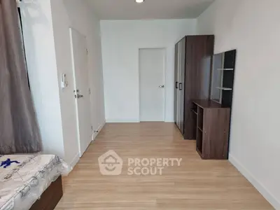 Spacious bedroom with wooden flooring and modern furniture in a minimalist design.