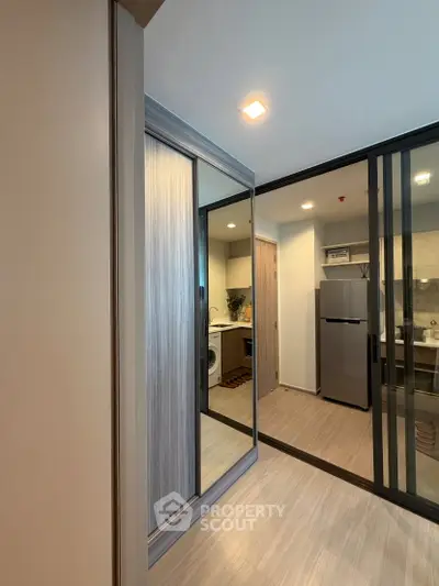 Modern apartment interior with sleek kitchen and laundry area, featuring stylish sliding glass doors.