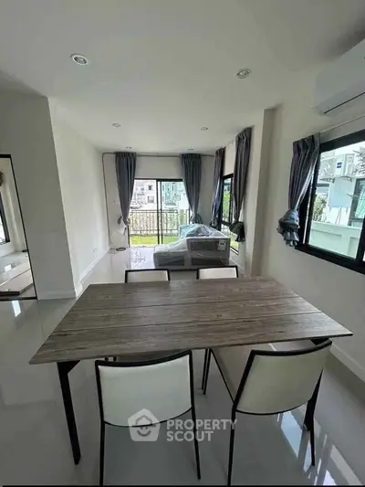Spacious modern living room with large windows and stylish dining area, offering abundant natural light.