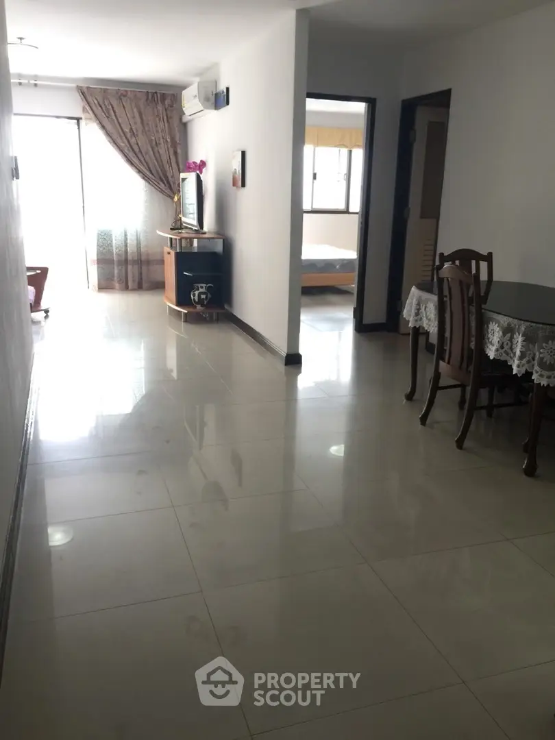 Spacious apartment hallway leading to a bright living area with elegant furnishings.