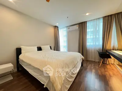 Spacious bedroom with modern decor and large windows for natural light.