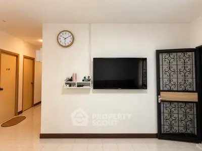 Modern living room with wall-mounted TV and stylish clock, featuring elegant door design.