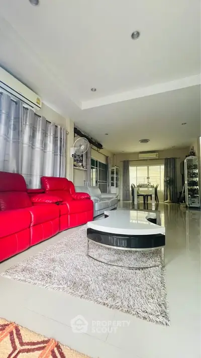 Spacious living room with modern red sofa and elegant decor, perfect for family gatherings.