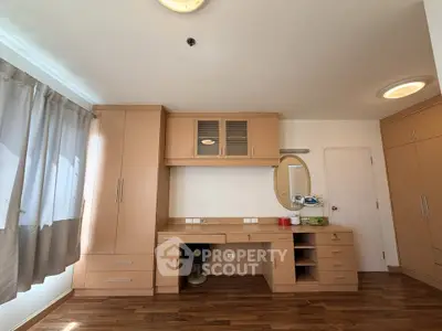 Spacious bedroom with built-in wooden cabinets and elegant hardwood flooring