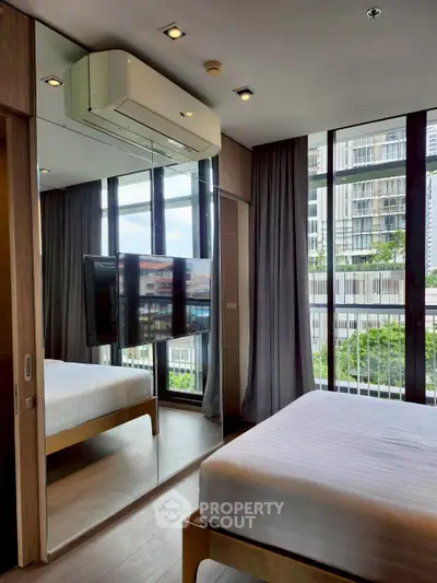 Modern bedroom with mirrored wardrobe and large windows offering city view