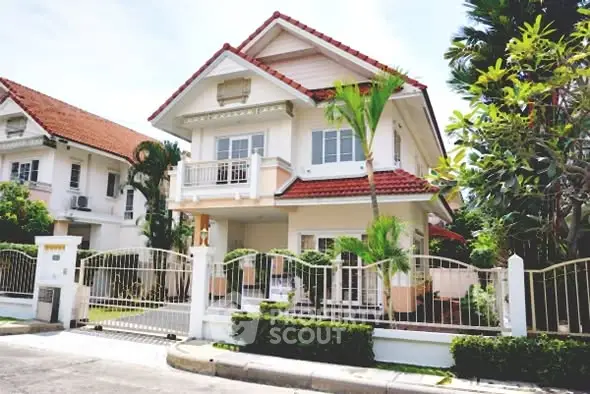 Charming two-story house with red roof and lush garden in suburban neighborhood.
