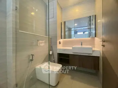 Modern bathroom with sleek design, featuring a glass shower and elegant vanity.