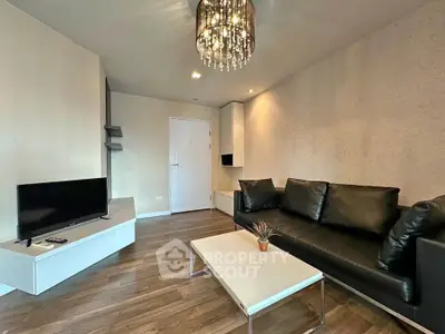 Modern living room with sleek black leather sofa and stylish chandelier