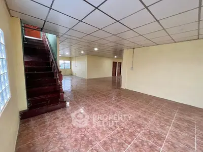 Spacious open-plan interior with tiled flooring and staircase, ideal for customization.