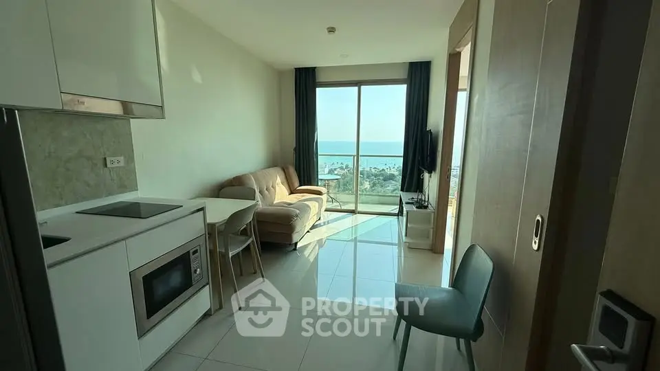 Modern apartment with ocean view, featuring sleek kitchen and cozy living area.